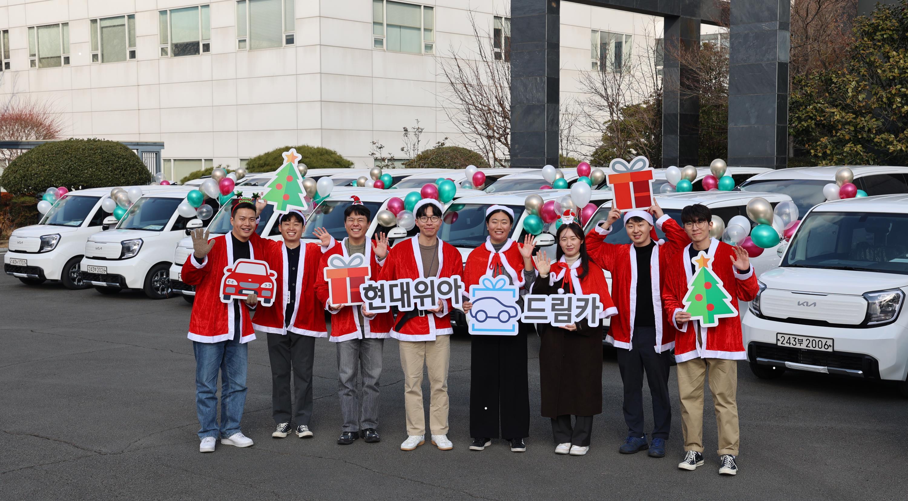 On December 21st, employees of HYUNDAI WIA are taking a photo in front of HYUNDAI WIA's headquarters in Changwon-si, Gyeongsangnam-do, with the ‘HYUNDAI WIA Dream Car,' which will be gifted to 20 local social welfare organizations. Courtesy of HYUNDAI WIA.